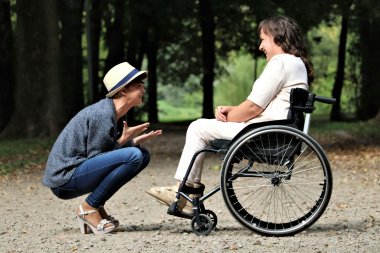 Frau im Rollstuhl und hockende Frau
